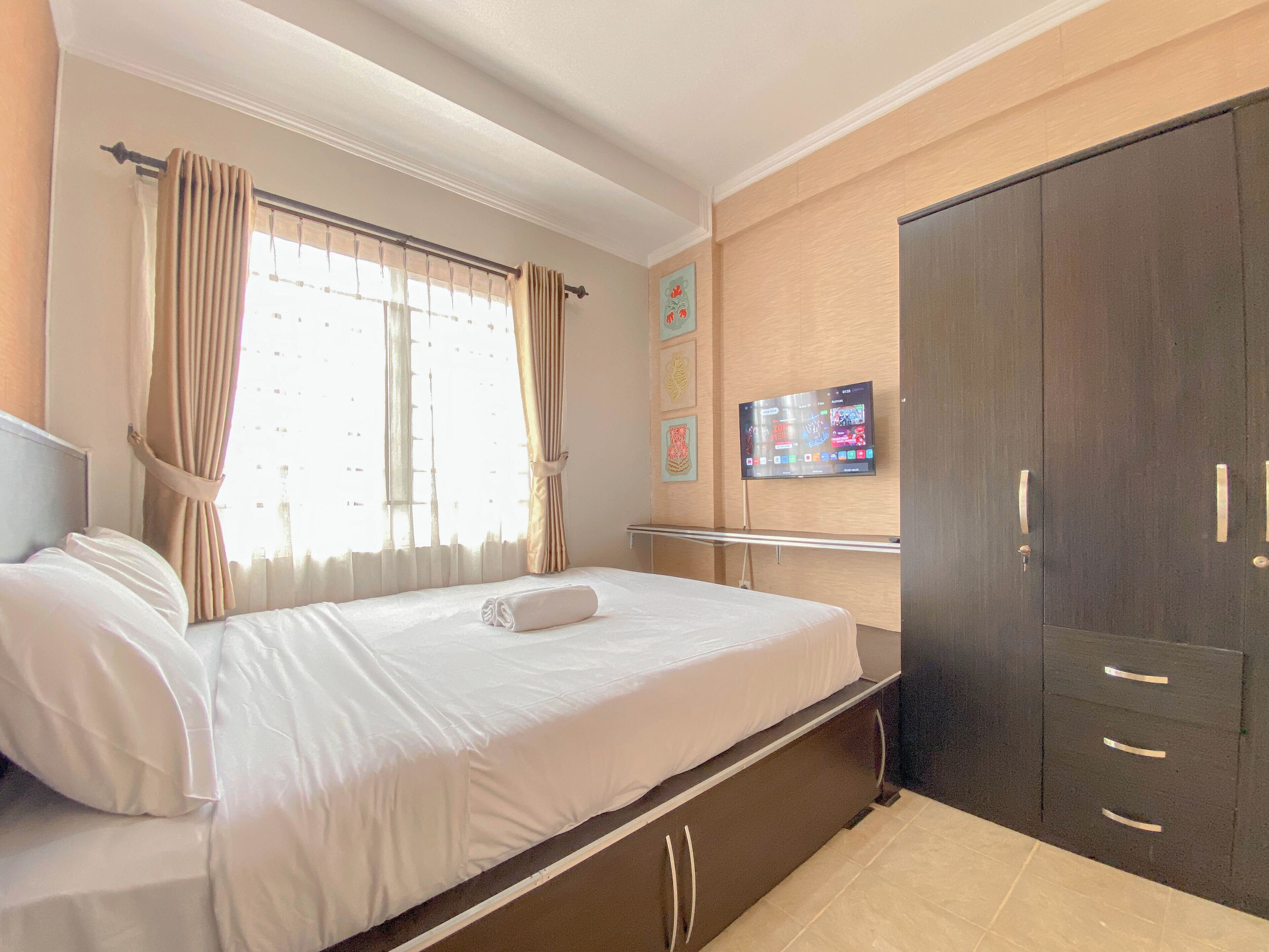 Una habitación de hotel con cama, cortinas, televisor en la pared y armario.