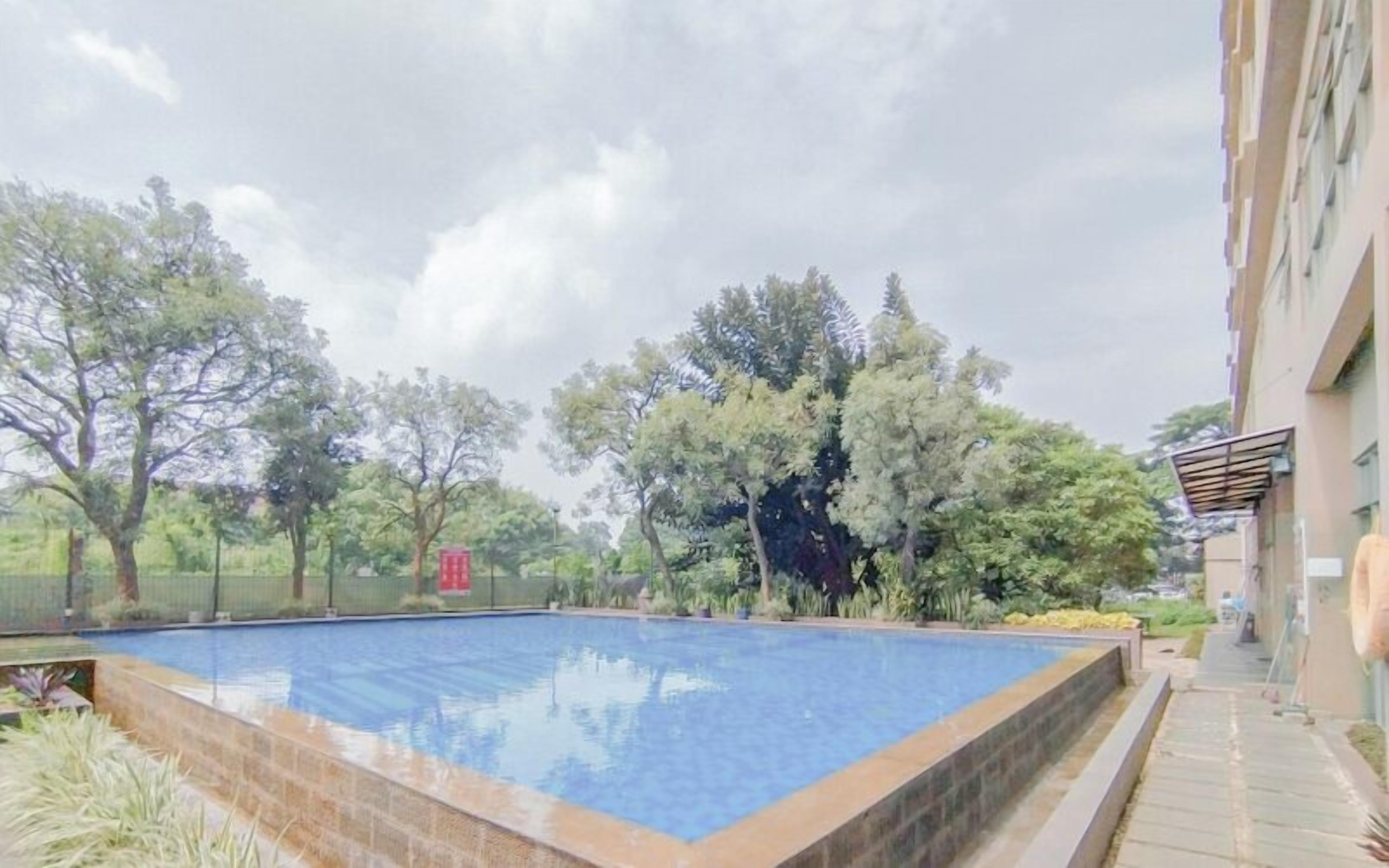 Una piscina rodeada de árboles y un edificio.