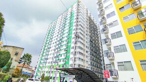 Un edificio residencial alto con varios balcones, un área exterior techada y un letrero de 'No Estacionar'.