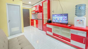 Una cocina moderna con armarios rojos y blancos, un dispensador de agua incorporado y un televisor de pantalla plana que muestra varios canales.