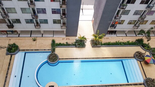 Piscina en la azotea rodeada de follaje con vistas a edificios cercanos.