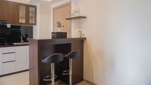 Une cuisine moderne équipée d’une cuisinière intégrée, d’une machine à café et d’un petit coin bar avec deux tabourets.