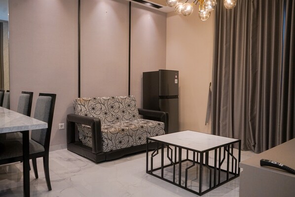A modern living room with a sofa, a dining table, and a TV stand. - Cozy 2Br Apartment M-Town Signature (Gading Serpong)