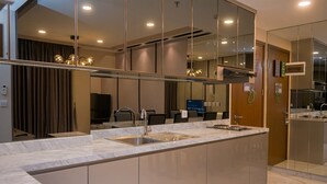 A modern kitchen with a marble countertop, stainless steel sink, and a built-in oven. - Cozy 2Br Apartment M-Town Signature (Gading Serpong)