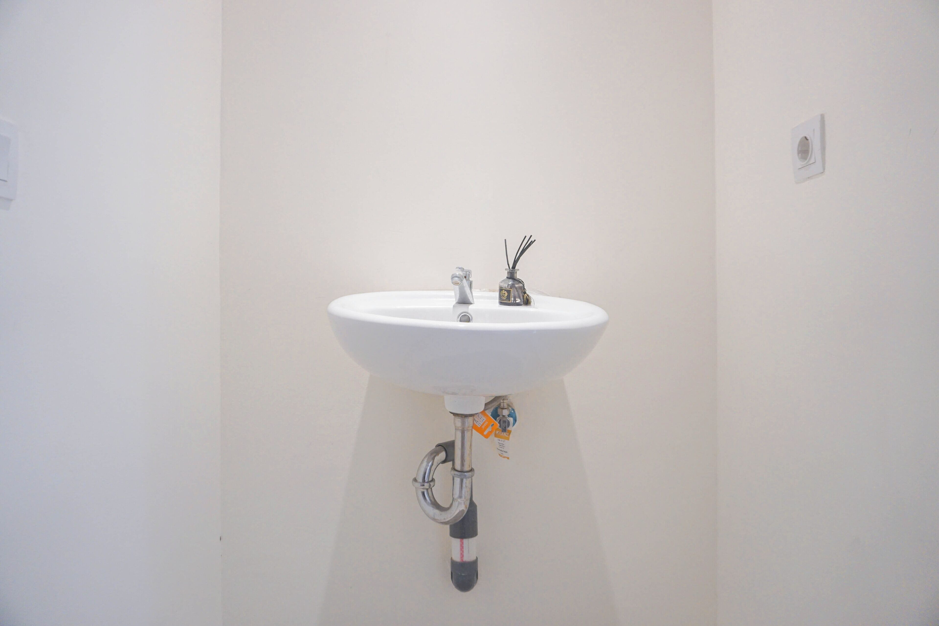 A white bathroom sink with a faucet and a small bottle of liquid soap.
