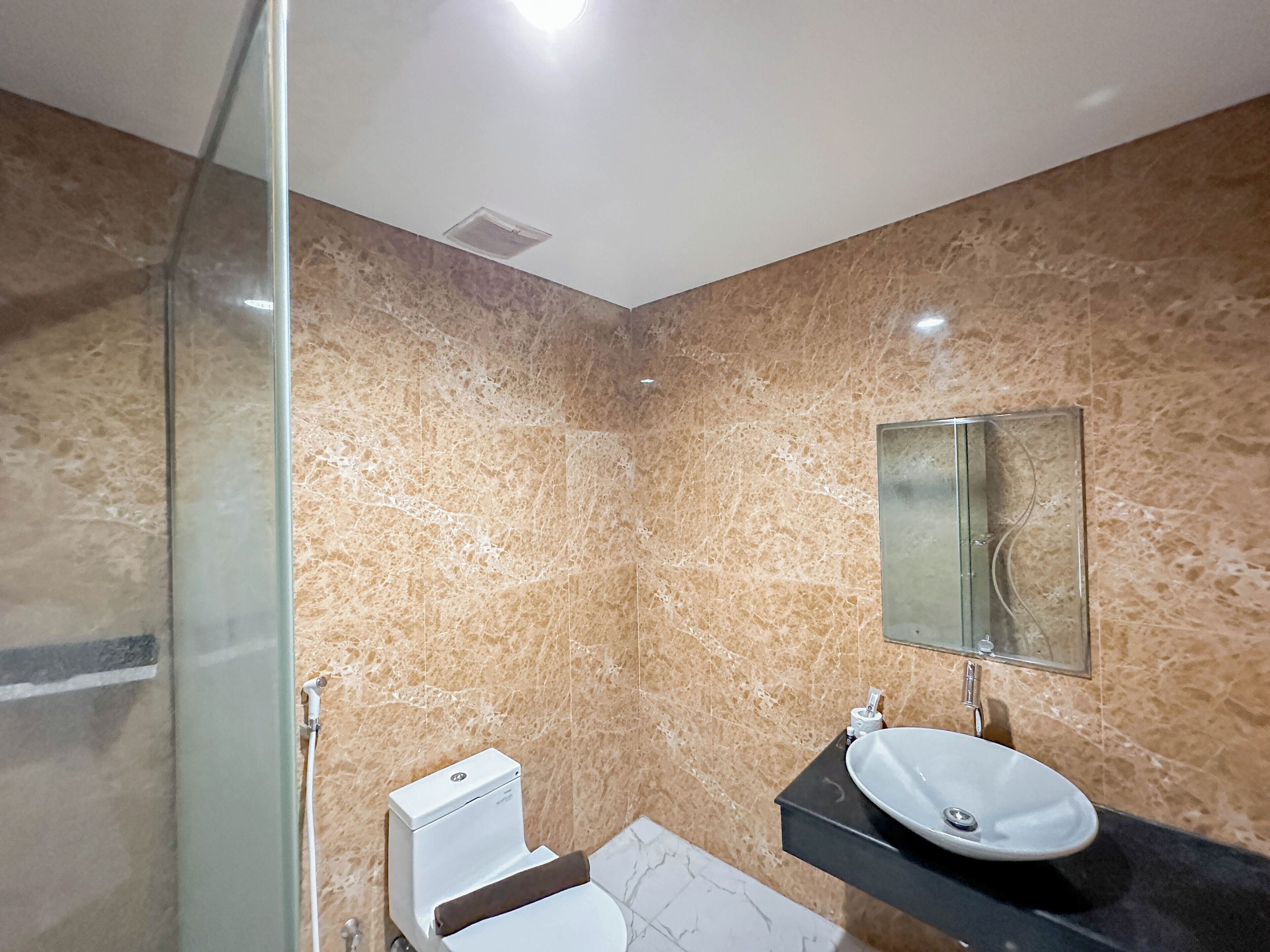 A bathroom with a toilet, sink, and mirror.