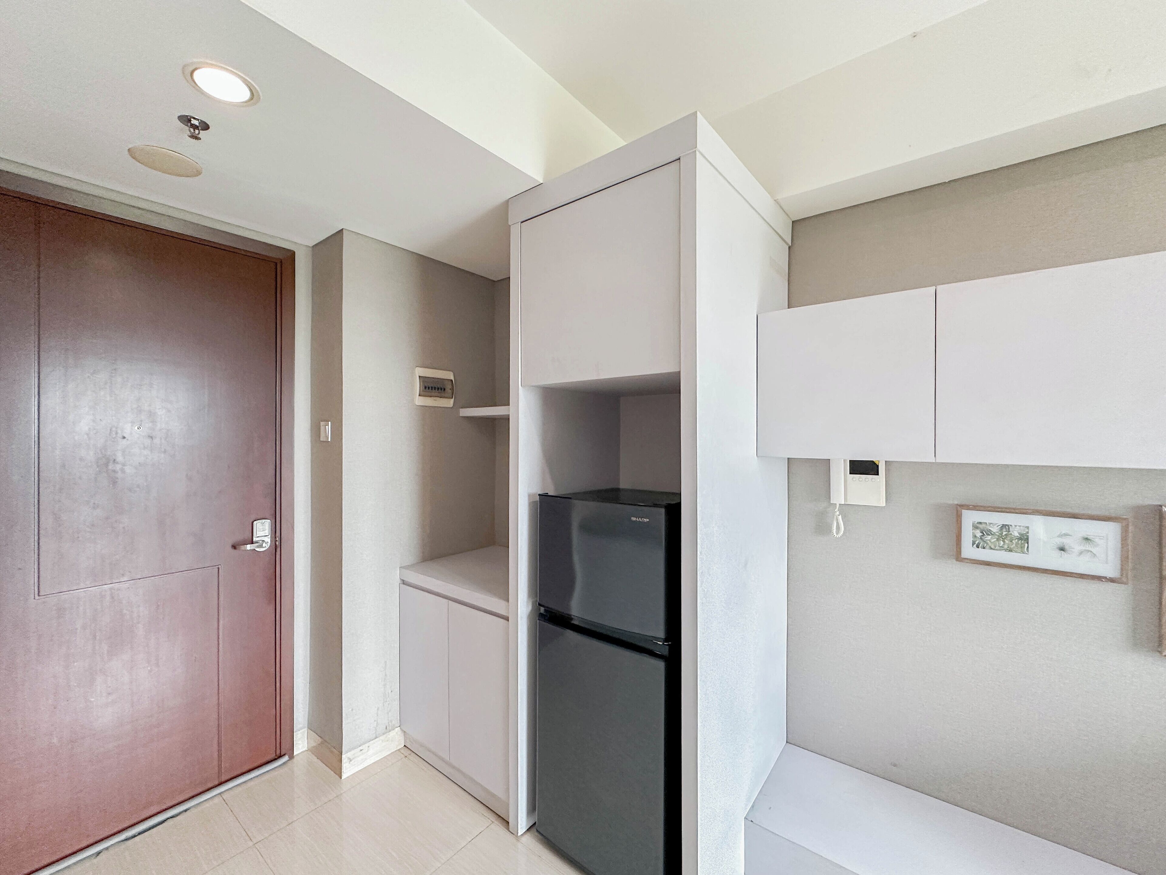 Una cocina compacta con refrigerador, armarios y una puerta.