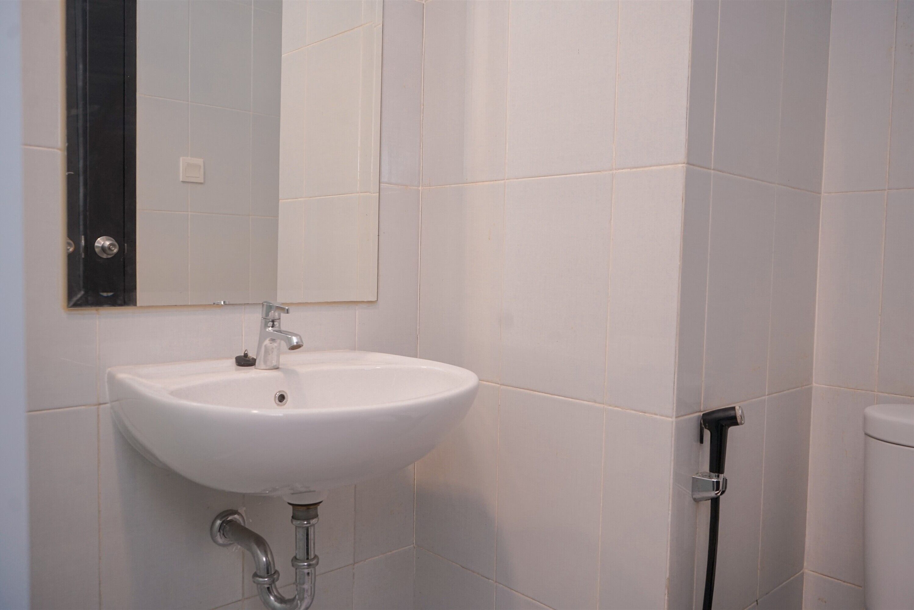 Un baño con lavamanos blanco, un espejo y un inodoro.