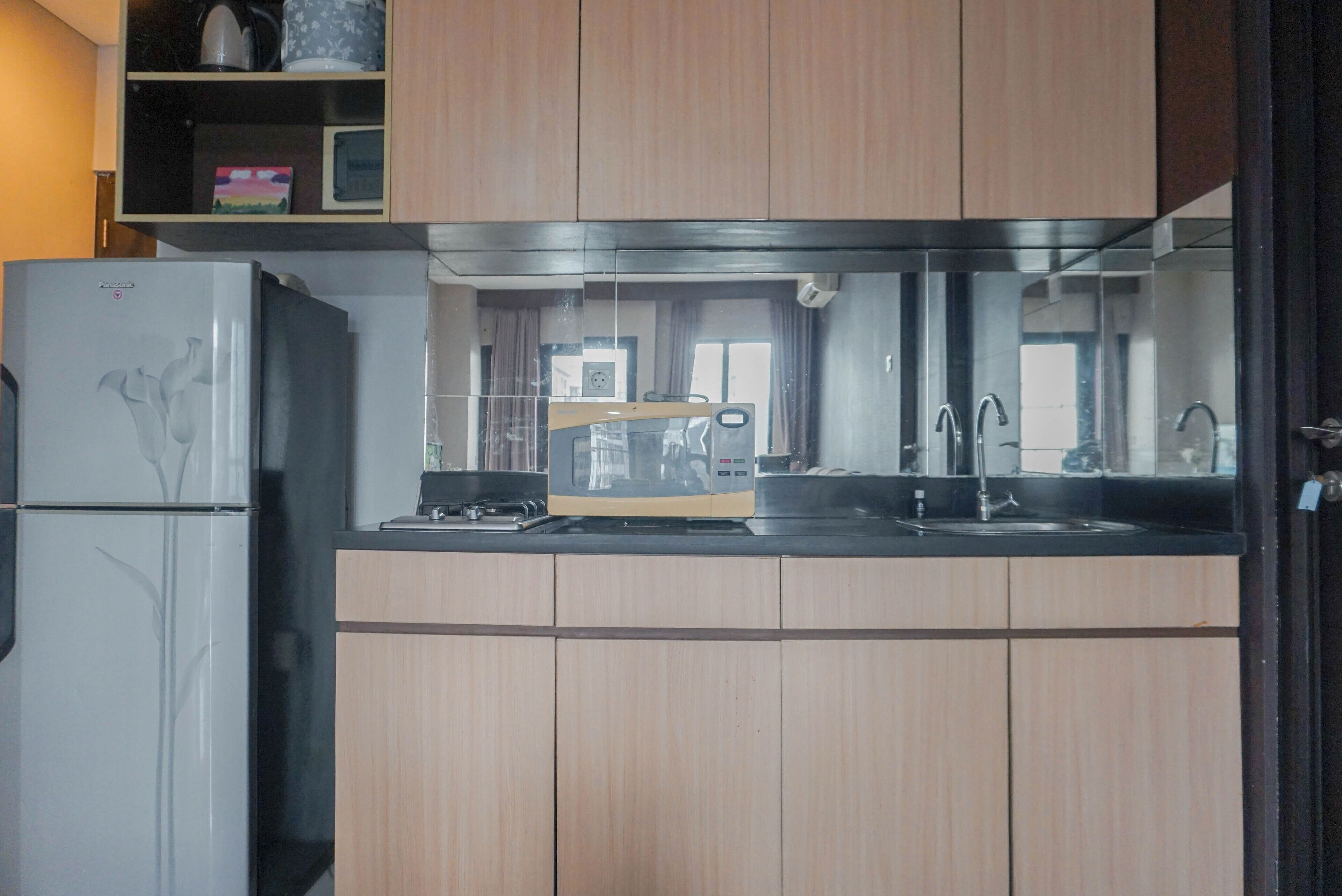 A kitchen with wooden cabinets, a refrigerator, a microwave, and a sink.