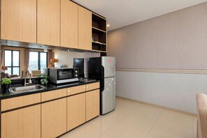 A modern kitchen with wooden cabinets, a stainless steel refrigerator, a microwave, and a sink.