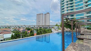 A rooftop pool with a view of high-rise buildings and a bridge in the background. - Comfy And Modern 2Br Grand Kamala Lagoon Apartment (Bekasi)