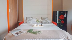 A neatly made bed with a tray of toiletries, a vase with flowers, and a magazine on the bed. - Cozy Studio Apartment At LRT City Jatibening (Bekasi)