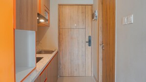 A narrow hallway with wooden cabinets, a sink, and a door. - Cozy Studio Apartment At LRT City Jatibening (Bekasi)