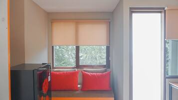Una habitación con cama, ventana con persianas y una pequeña mesa.