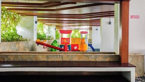 A children's play area with colorful equipment and a stone-tiled floor.