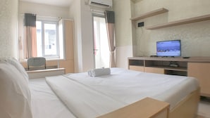 Une chambre d’hôtel avec un lit, un bureau avec un ordinateur, une chaise et une fenêtre avec des rideaux.