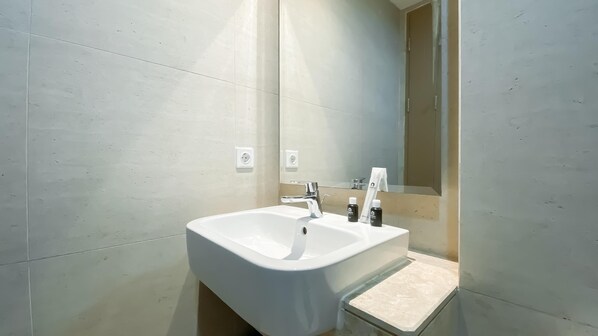 A modern bathroom with a white sink, a mirror, and a towel hanging on the wall. - Brand New And Homey Studio At Gold Coast Apartment Pik (Jakarta)