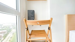 Een houten stoel met rugleuning en zitvlak, geplaatst bij een raam met uitzicht op een stadsbeeld.