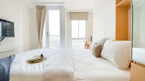 Een hotelkamer met een bed, een aan de muur bevestigde televisie en een balkon met uitzicht.