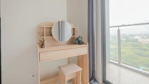 A modern bedroom with a wooden desk, a round mirror, a small stool, and a potted plant. - Modern And Comfy Studio At Daan Mogot City Apartment (Jakarta)