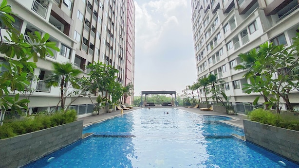 A swimming pool surrounded by high-rise residential buildings with balconies. - Good Choice and Comfy Studio Apartment at LRT City Jatibening (Bekasi)