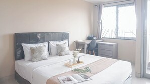 A hotel room with a bed, a desk, and a window with curtains. - Good Choice and Comfy Studio Apartment at LRT City Jatibening (Bekasi)