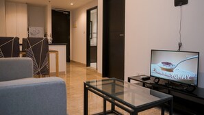 Una sala de estar moderna con una mesa de centro de vidrio, un televisor de pantalla plana y un sofá.
