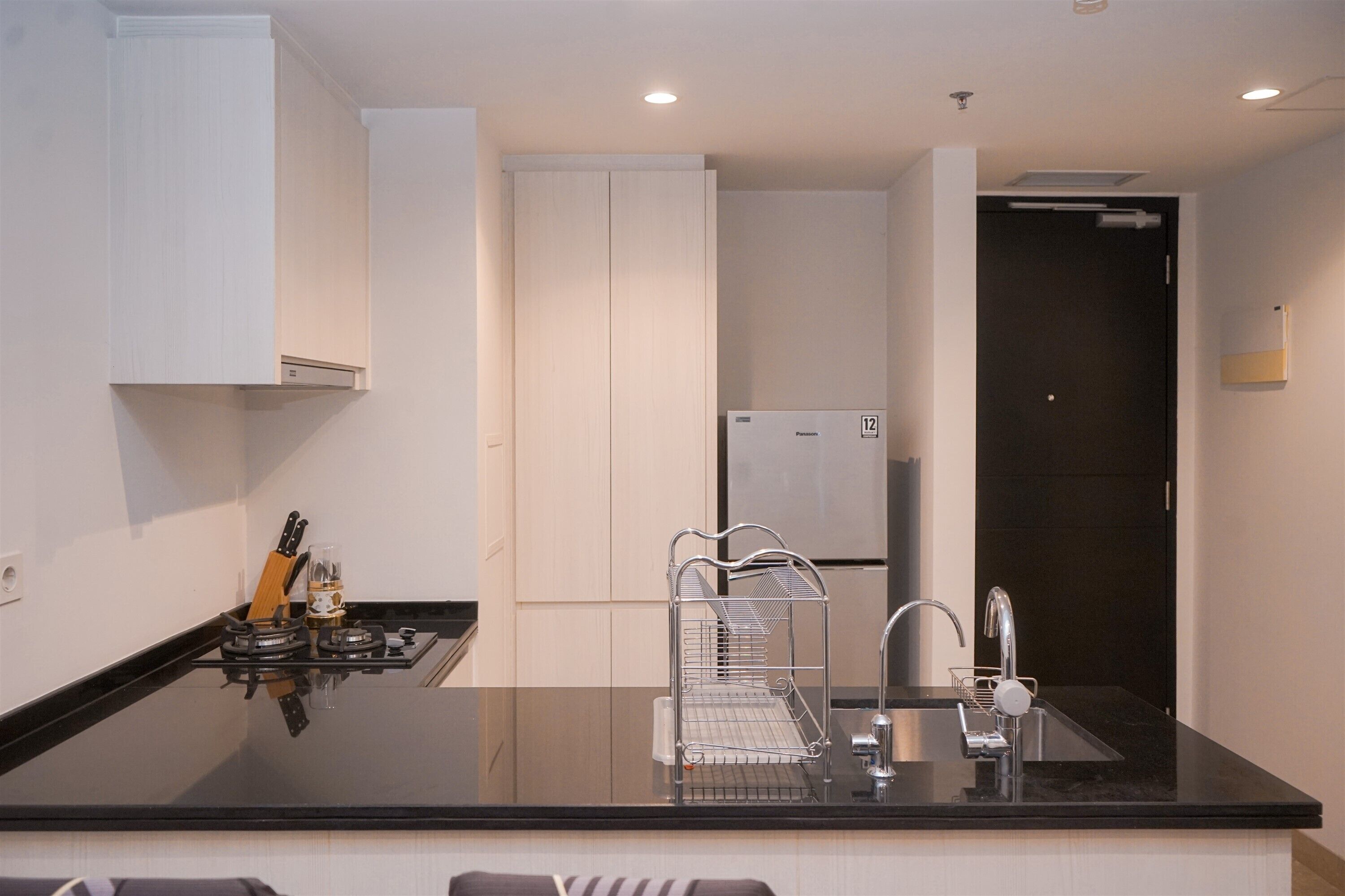 Una cocina moderna con encimera negra, pileta de acero inoxidable y muebles de cocina blancos.