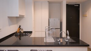 Una cocina moderna con encimera negra, pileta de acero inoxidable y muebles de cocina blancos.
