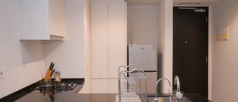 Una cocina moderna con encimera negra, pileta de acero inoxidable y muebles de cocina blancos.