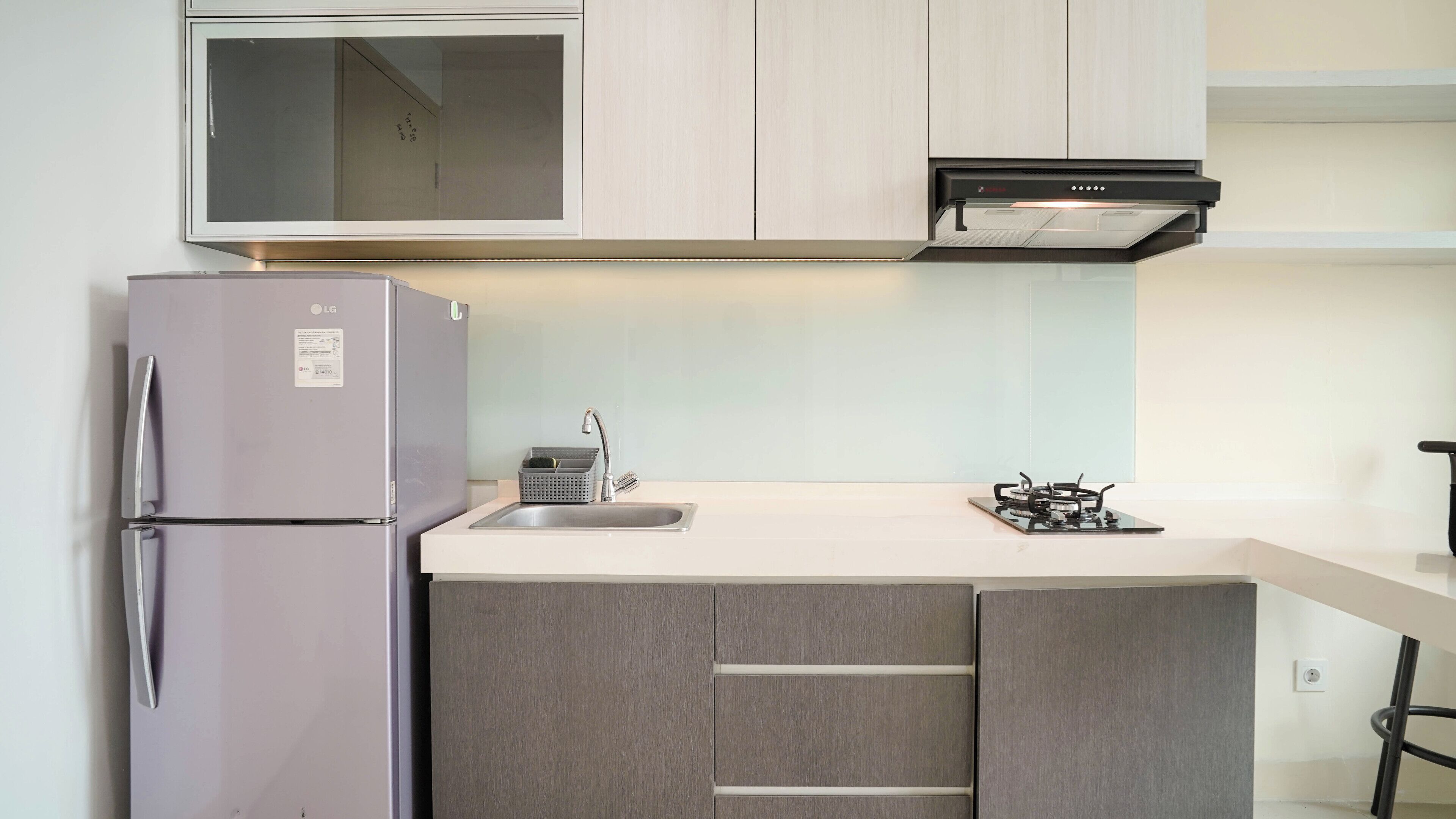 A compact kitchen with a refrigerator, a sink, a gas stove, and a microwave.