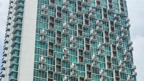 A high-rise building with a modern architectural design, featuring a grid of balconies and large windows.