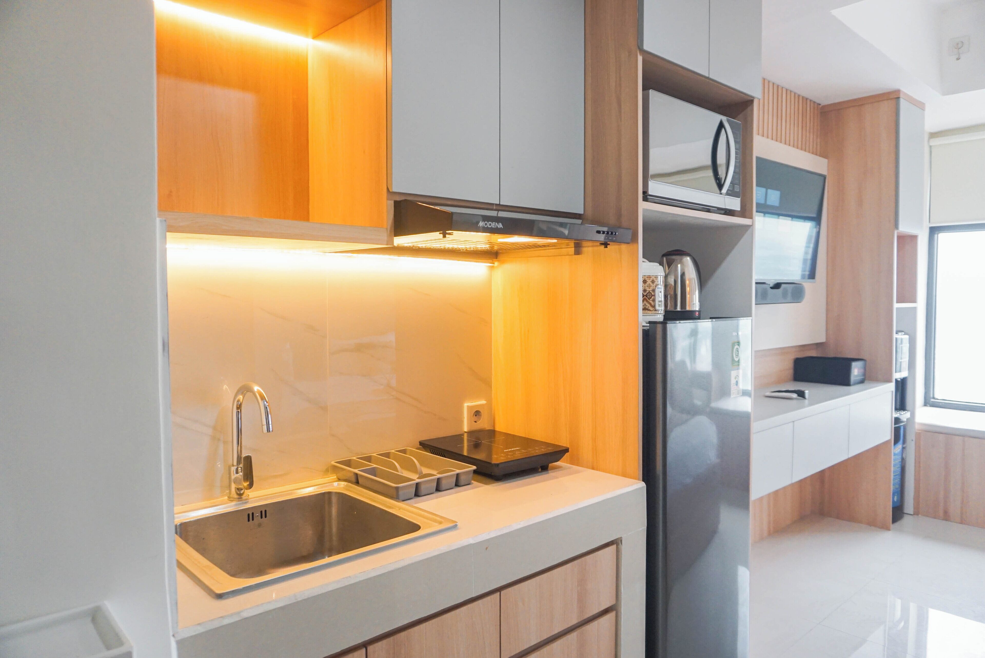 A modern kitchen with a stainless steel sink, a built-in oven, and wooden cabinetry.