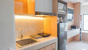 Une cuisine moderne dotée d’un évier en acier inoxydable, d’un four encastré et de meubles de rangement en bois.