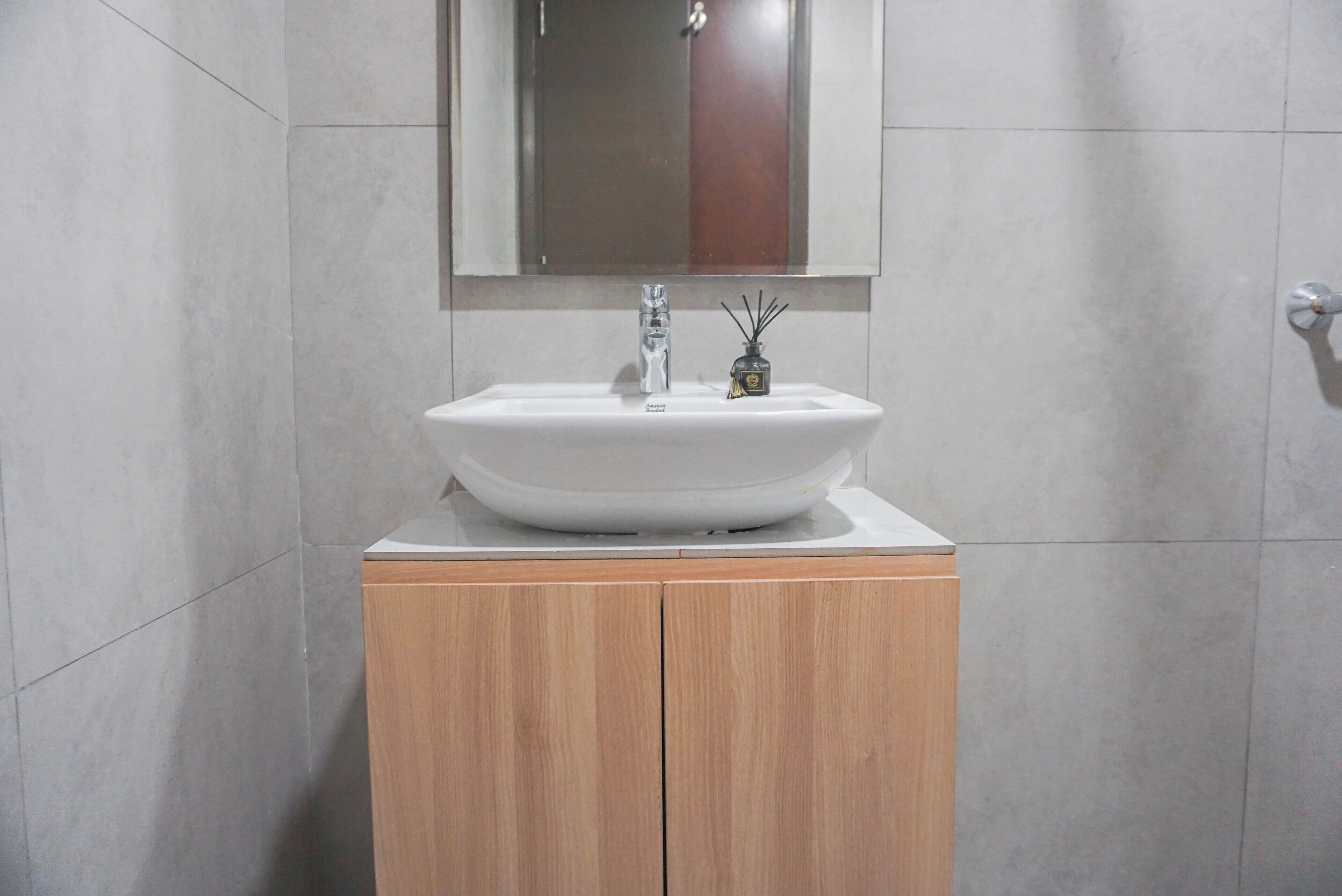 A bathroom with a white sink, wooden cabinet, and a mirror above the sink.