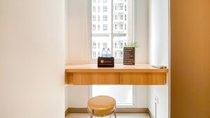 A small window seat with a wooden ledge, a travel bag, a bottle of water, and a sign listing travel destinations.