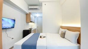 Une chambre d’hôtel équipée d’un lit, d’un téléviseur fixé au mur, d’une kitchenette et d’un appareil de climatisation.