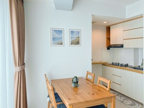 A modern kitchen with white cabinets, a wooden countertop, and a black range hood. - Comfort And Spacious 2Br Grand Kamala Lagoon Apartment (Bekasi)