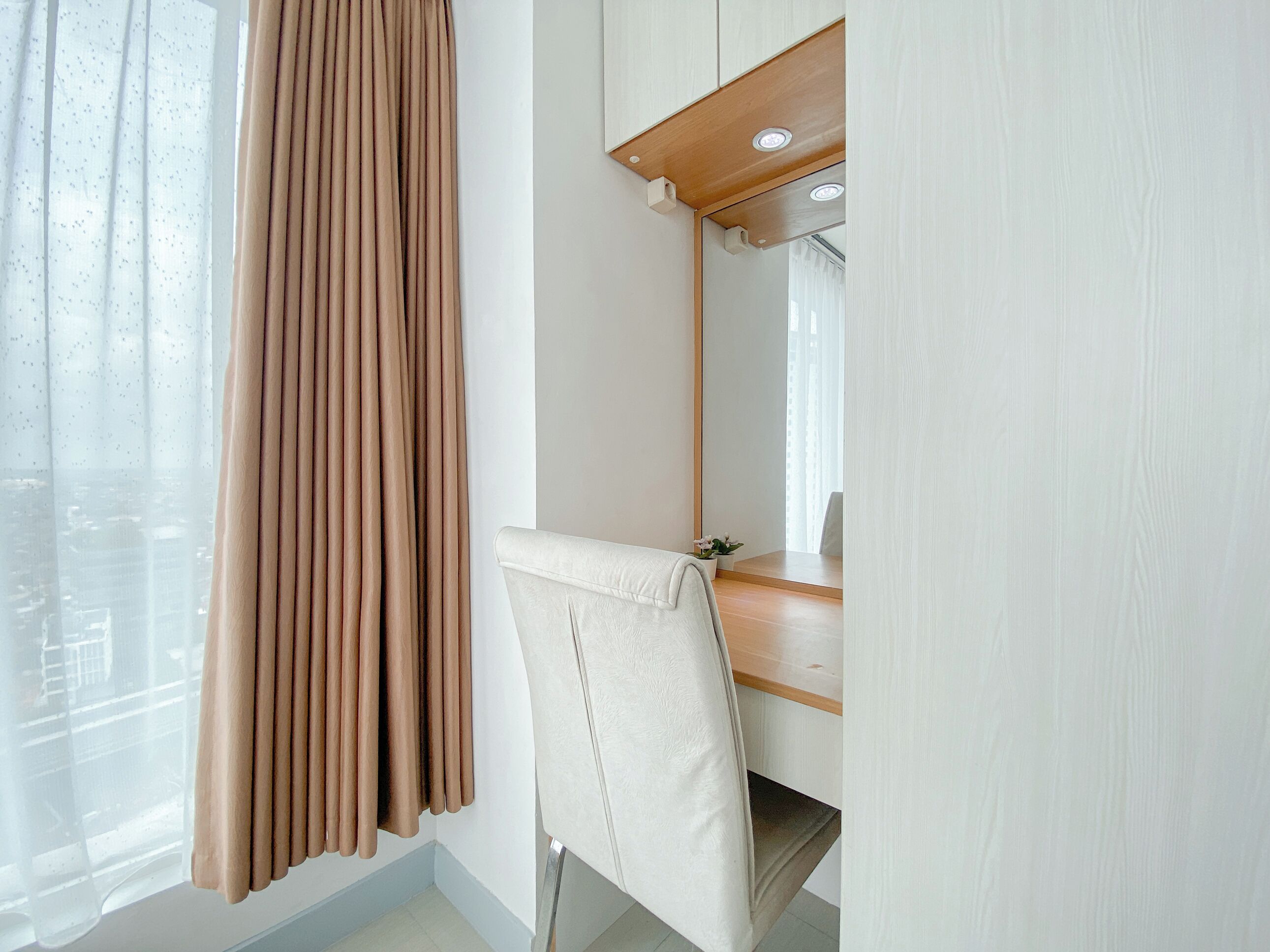 A room with a large mirror, a wooden desk, and a chair.