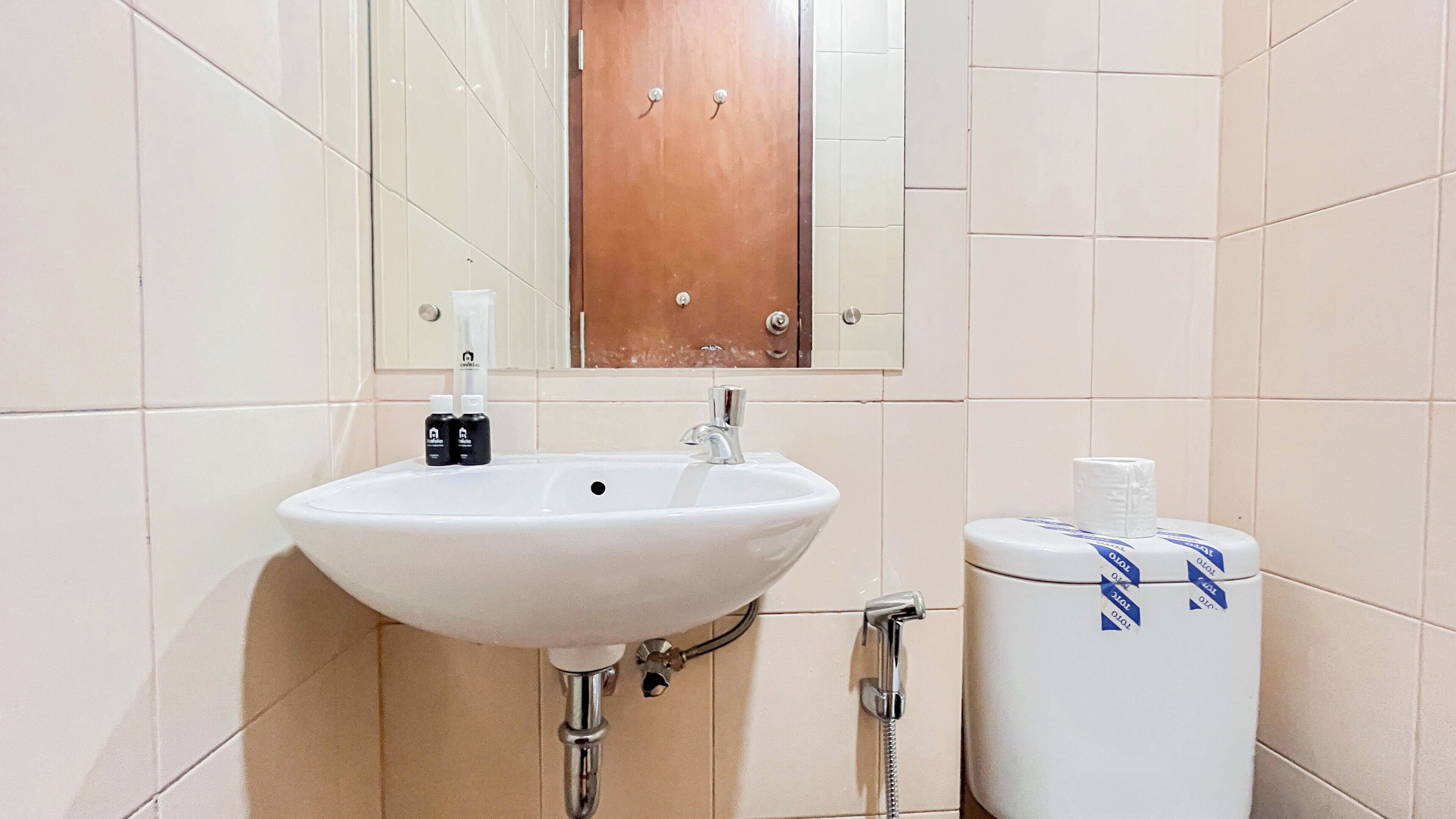 A bathroom with a white sink, a mirror, and a toilet.