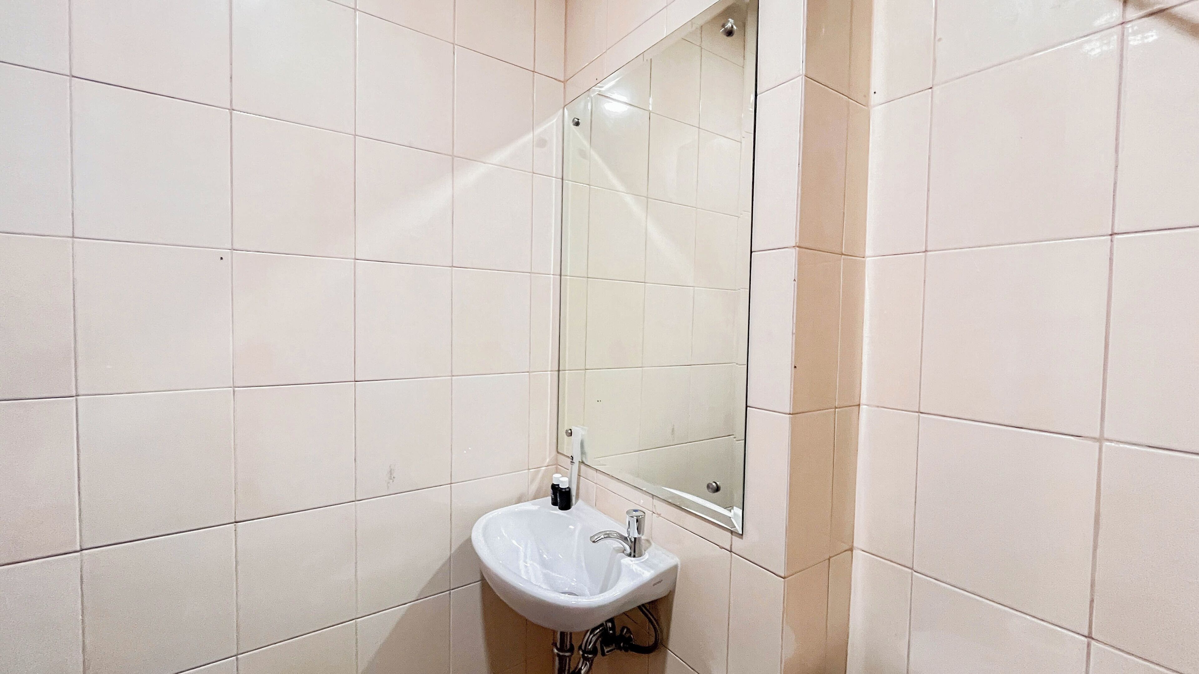A bathroom with white tiles, a sink, and a mirror.