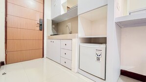 Una cocina compacta con armarios blancos, un lavamanos empotrado y una puerta de madera.