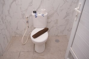 Bathroom features a toilet, shower area with showerhead and control panel, and a towel.
