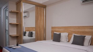 A hotel room with a large bed, wooden headboard, and a wardrobe with a mirror. - Comfy Designed Studio Apartment At Anwa Residence (South Tangerang)