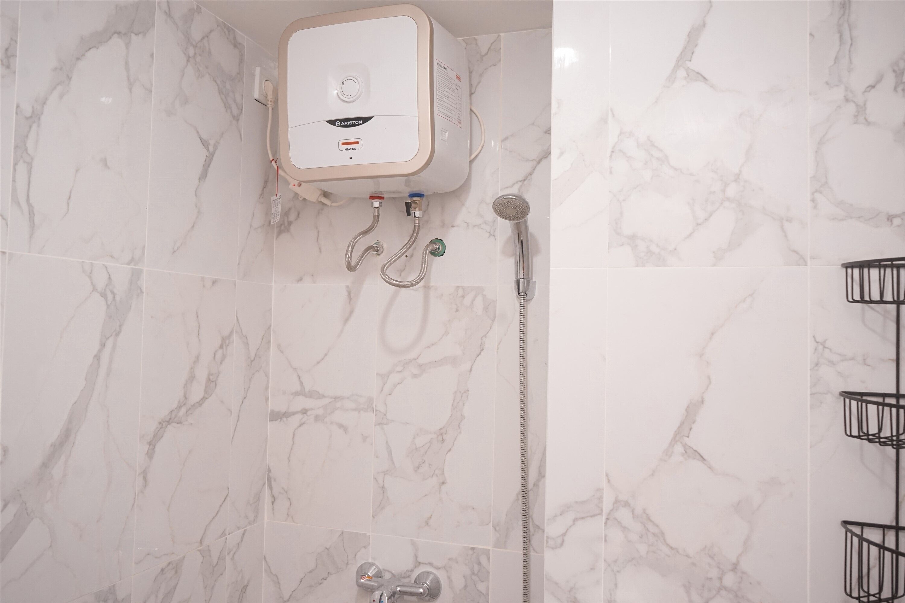 A bathroom with a wall-mounted heater, a showerhead, and a faucet.