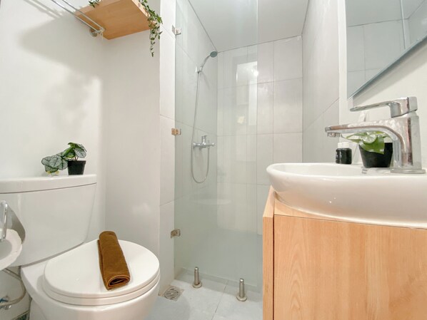 Une salle de bain moderne équipée de toilettes, d’une douche, d’un lavabo et d’un miroir.