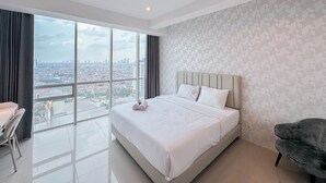 Een moderne hotelkamer met een groot bed, uitzicht op de stad en een balkon met een stoel.