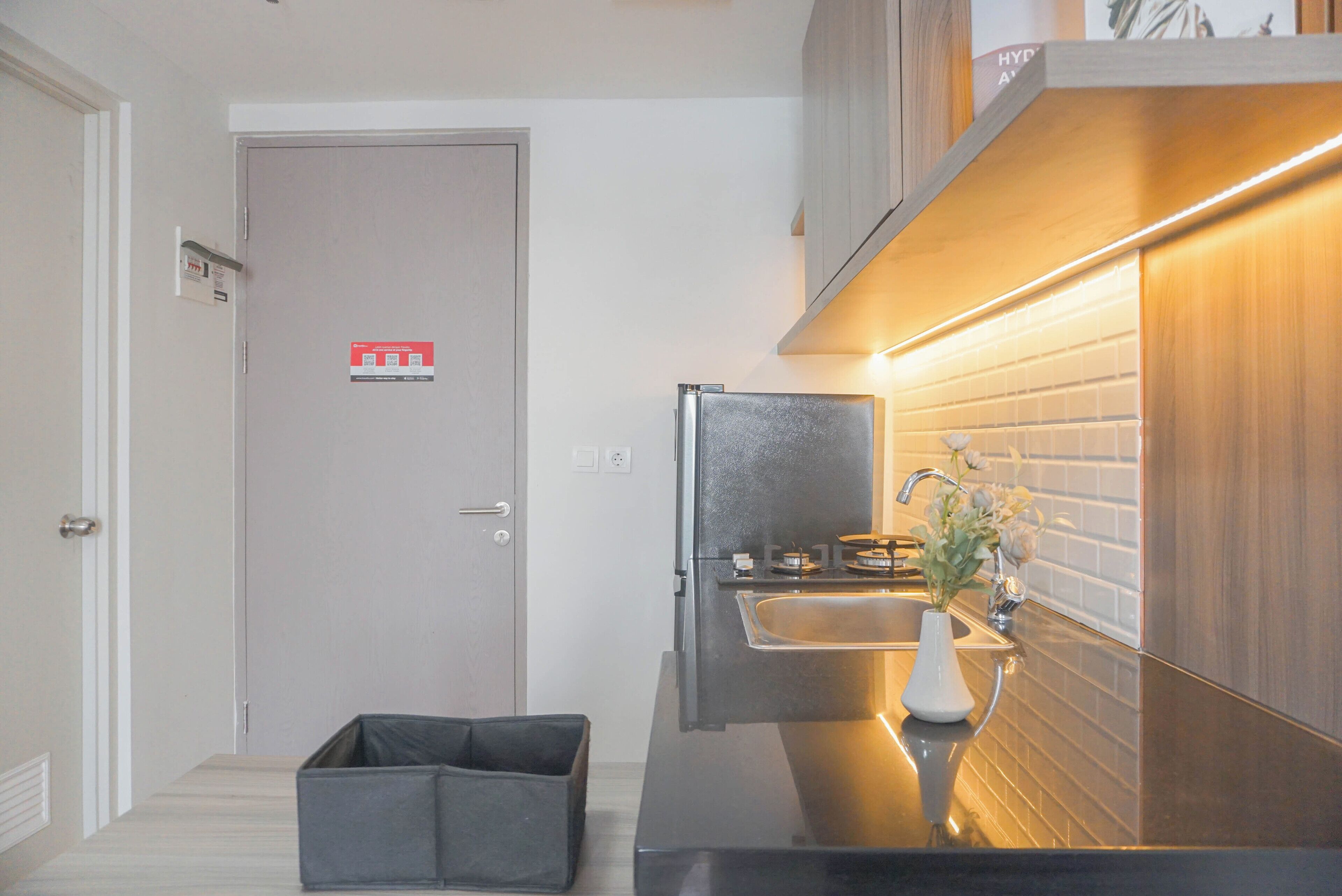 A compact kitchen with a built-in sink, a small countertop, and a dark-colored refrigerator.