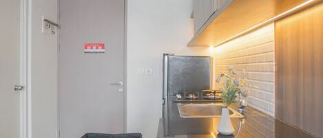 Una cocina compacta con un lavamanos integrado, una pequeña encimera y un refrigerador de color oscuro.
