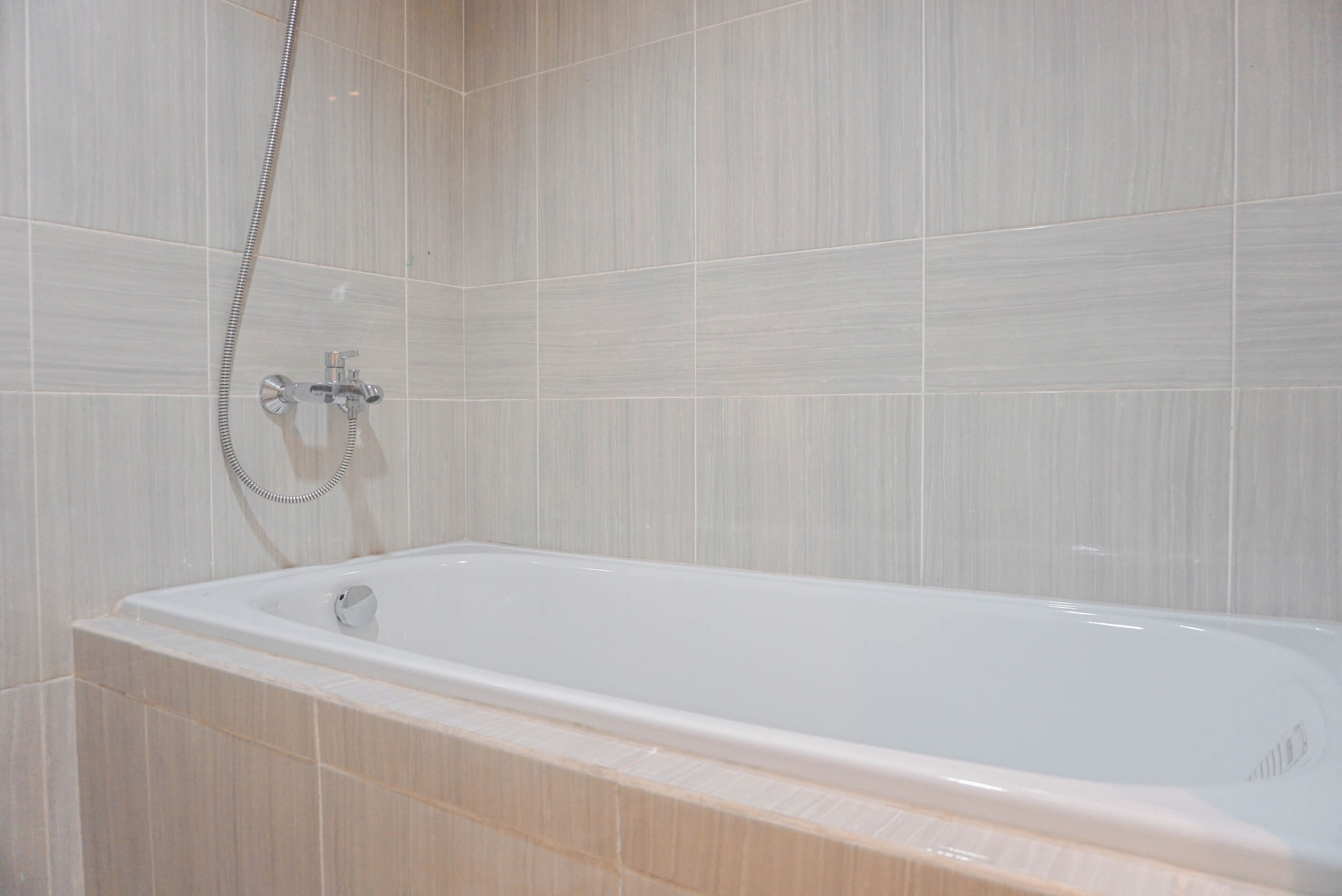 A modern bathroom with a freestanding bathtub, a showerhead, and tiled walls.